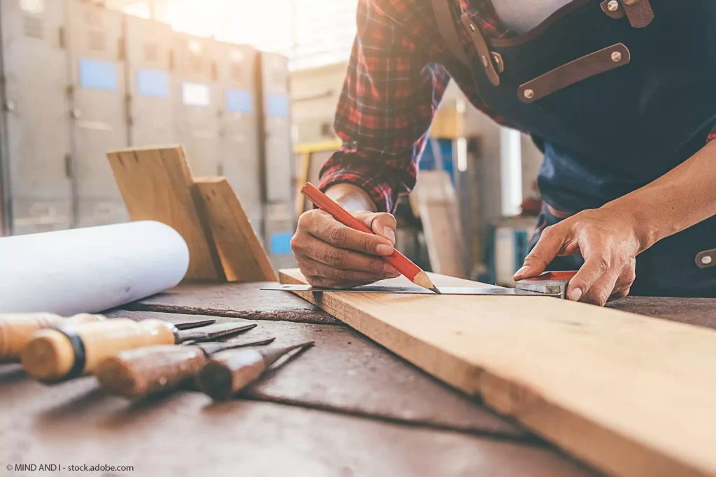 Praxis für Ergotherapie Boettcher in Greifswald - Behandlungsbereich -Handwerk-Werkstatt-im Fokus Handwerker zeichnet mit Bleistift auf einem Holzbrett an